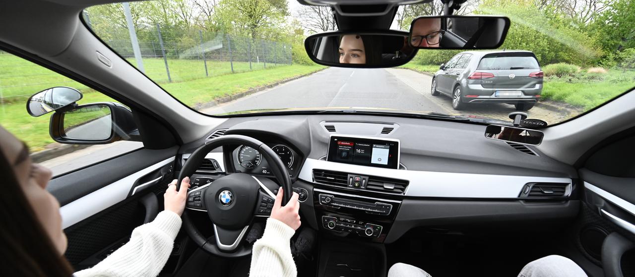 Eine Fahrschülerin, die den Führerschein mit 17 erwerben möchte, fährt Auto in ihrer Fahrstunde.