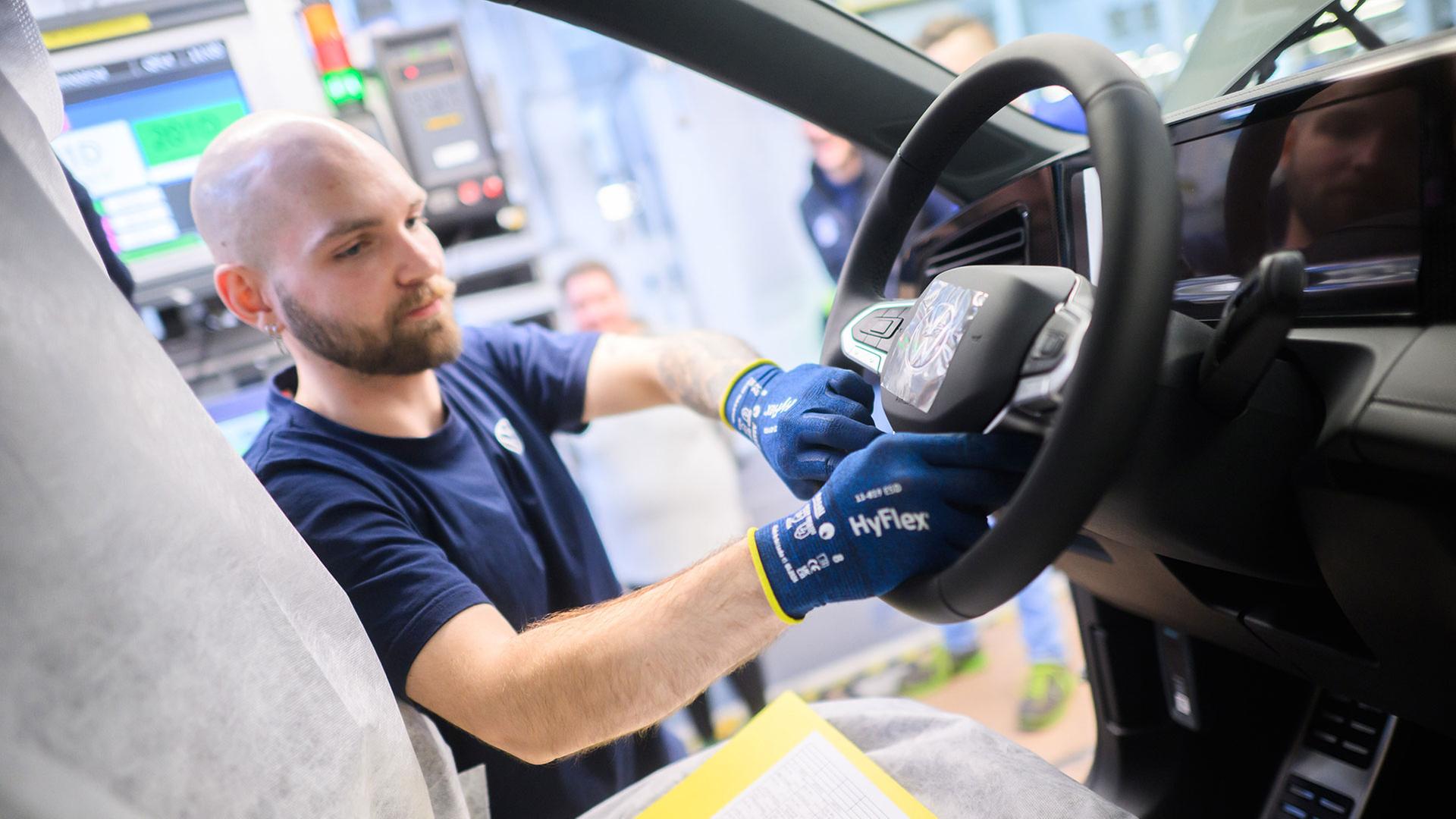 Ein Mitarbeiter montiert einen Airbag in einen Neuwagen Volkswagen Tiguan. | picture alliance/dpa