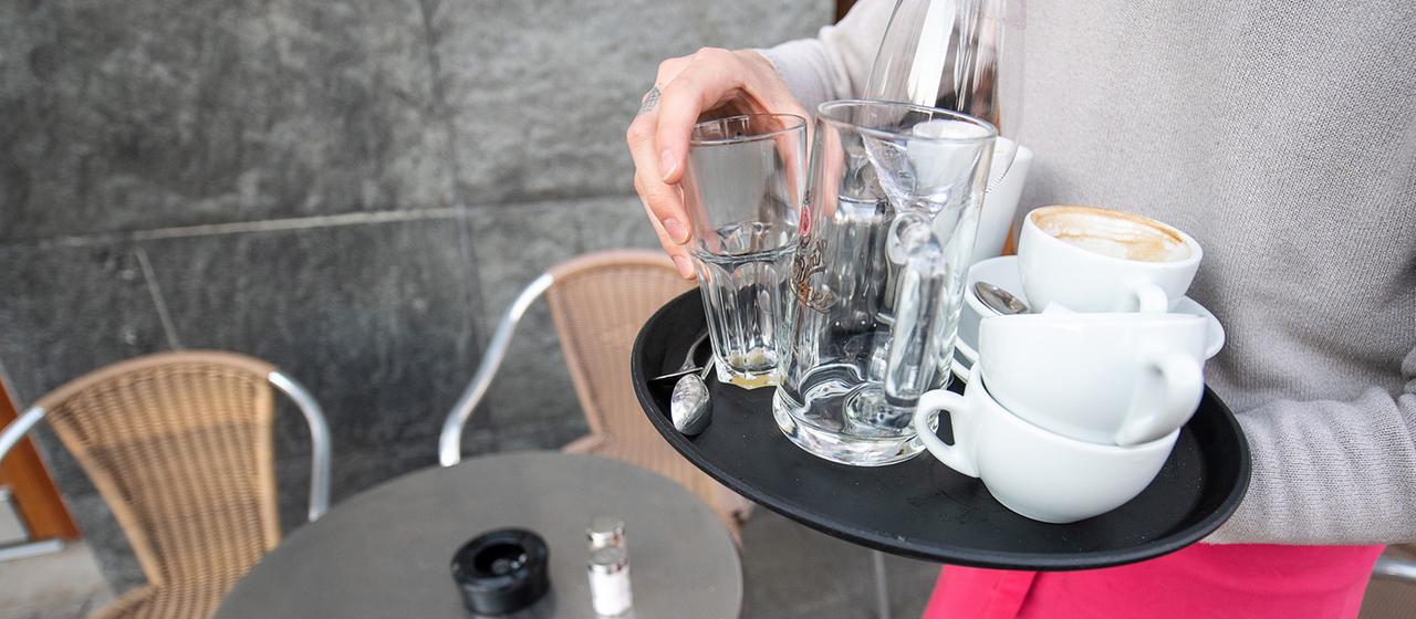 Ein Kellner räumt einen Tisch in einem Café ab. 