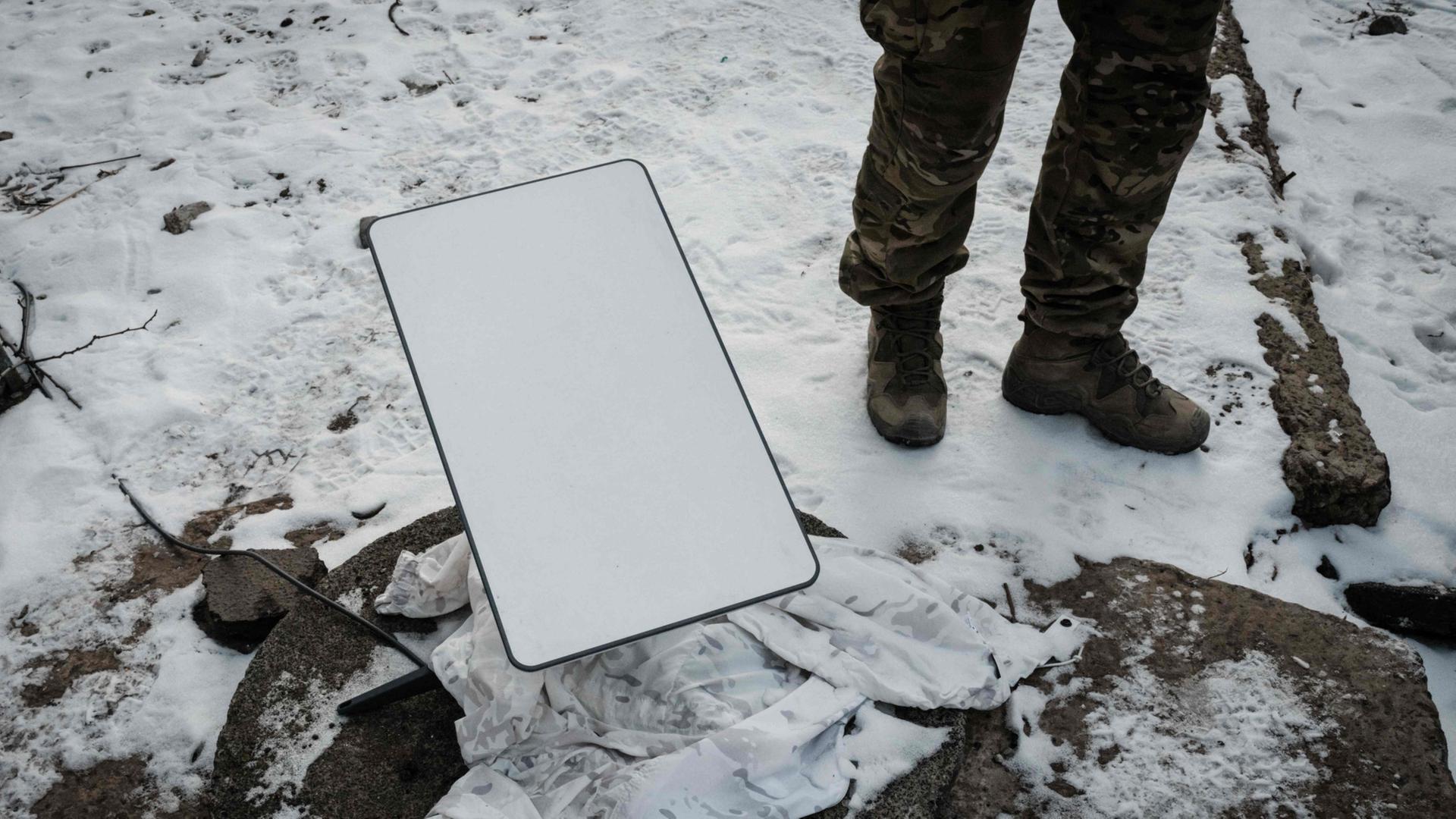 Ein ukrainischer Soldat steht neben einer Starlink-Antenne (Archivbild) | AFP