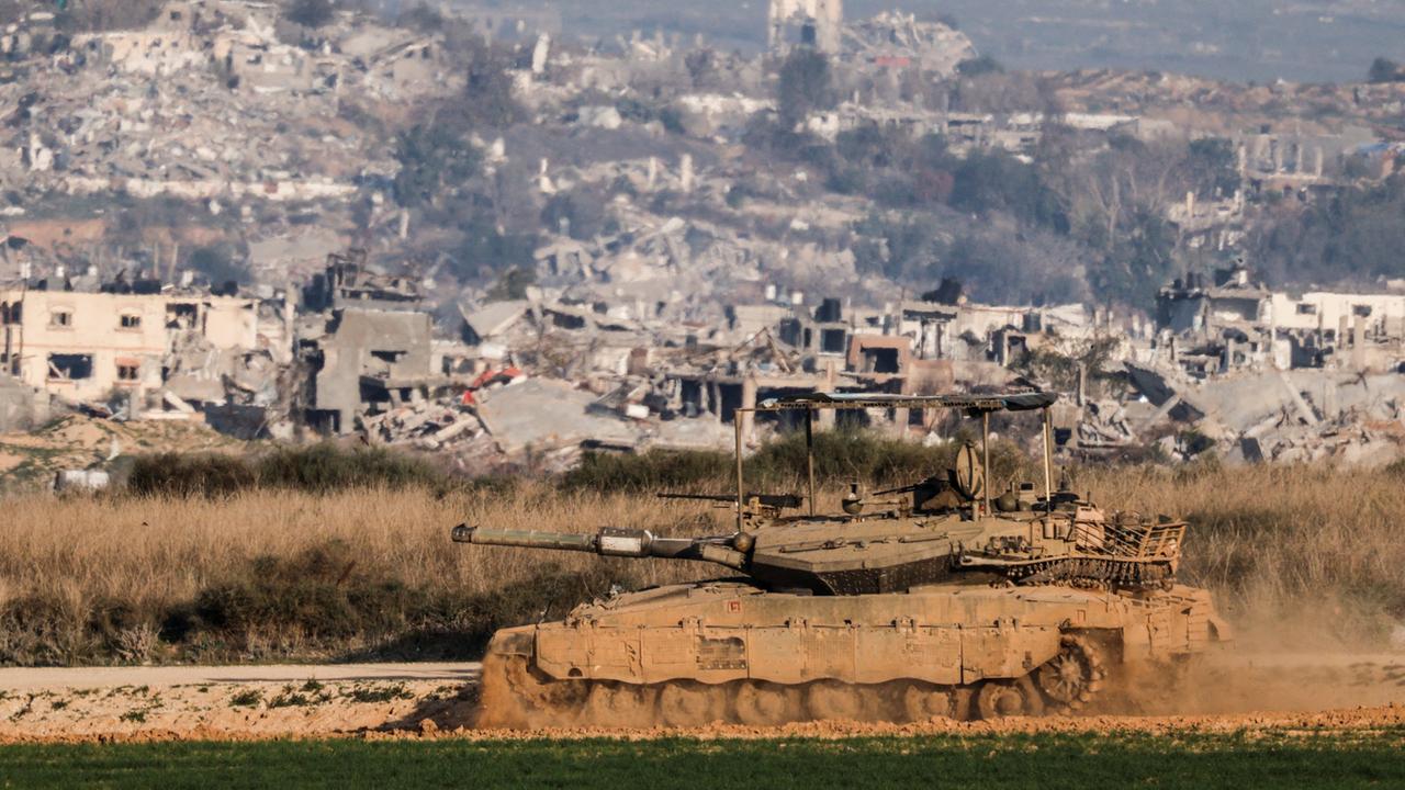 Ein Panzer an der südlichen Grenze Israels zum Gazastreifen, im Hintergrund sind zerstörte Häuser zu sehen. | REUTERS