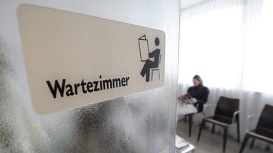 Eine Patientin sitzt in einem Wartezimmer einer Zahnarztpraxis.