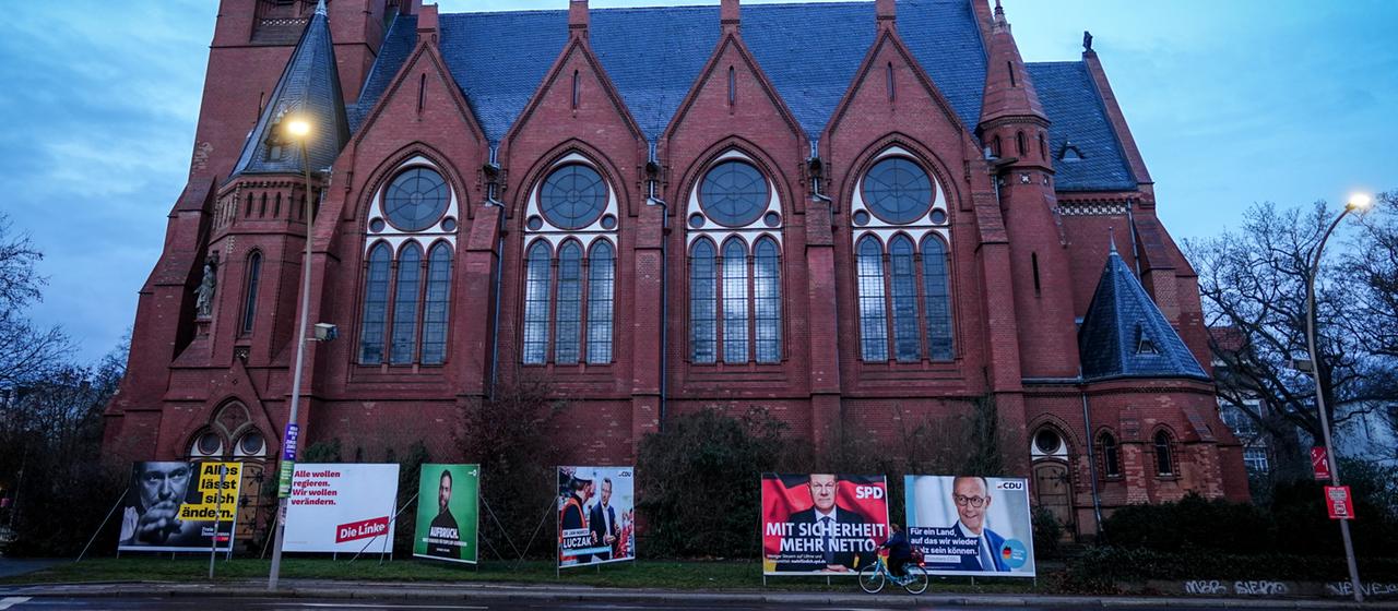 Wahlplakate der FDP, Die Linke, Bündnis 90/Die Grünen, SPD und CDU stehen vor einer Kirche.