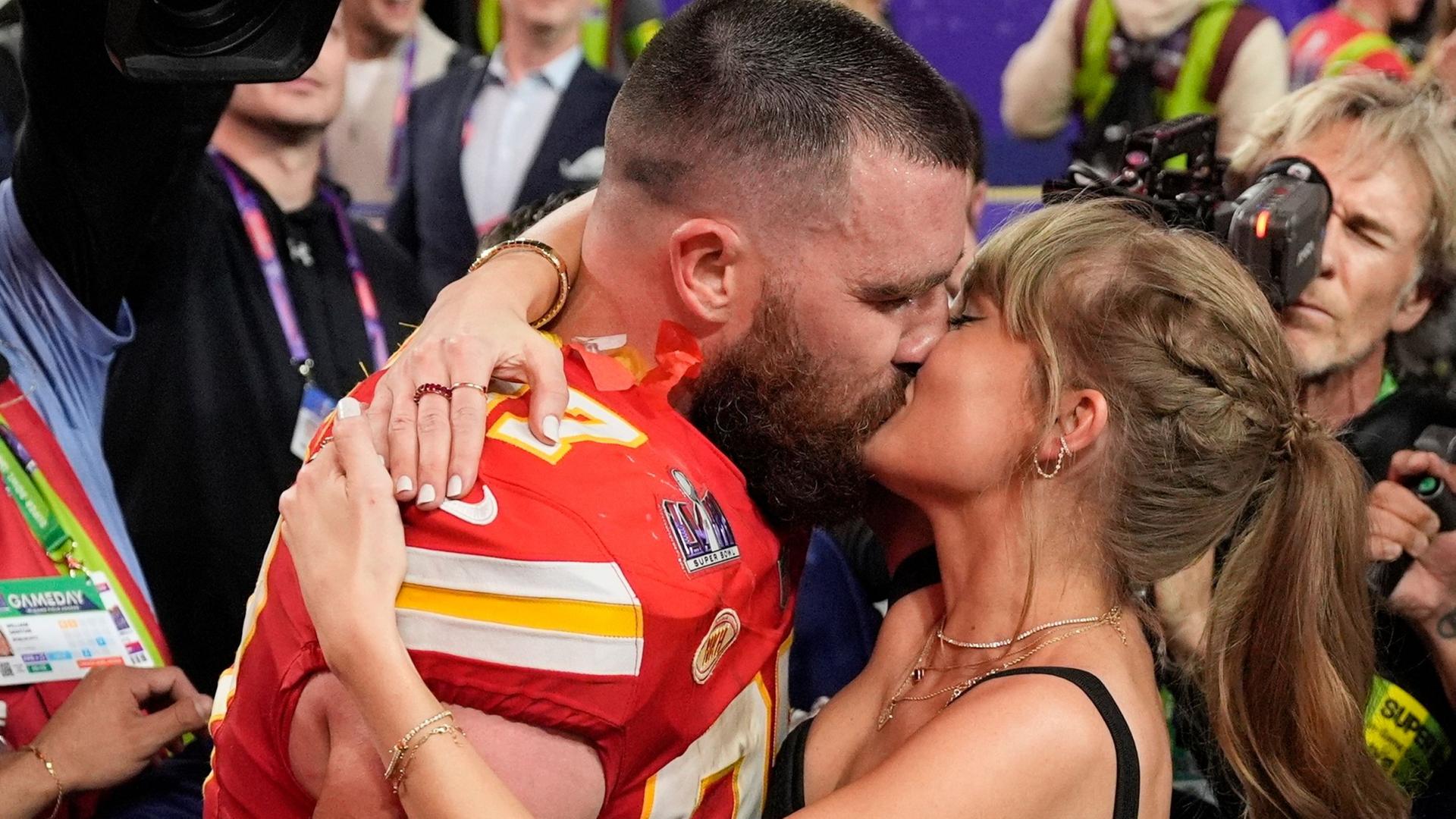Taylor Swift und Travis Kelce küssen sich. | John Locher/AP/dpa