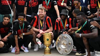 Spieler von Bayer Leverkusen mit Pokal und Meisterschale