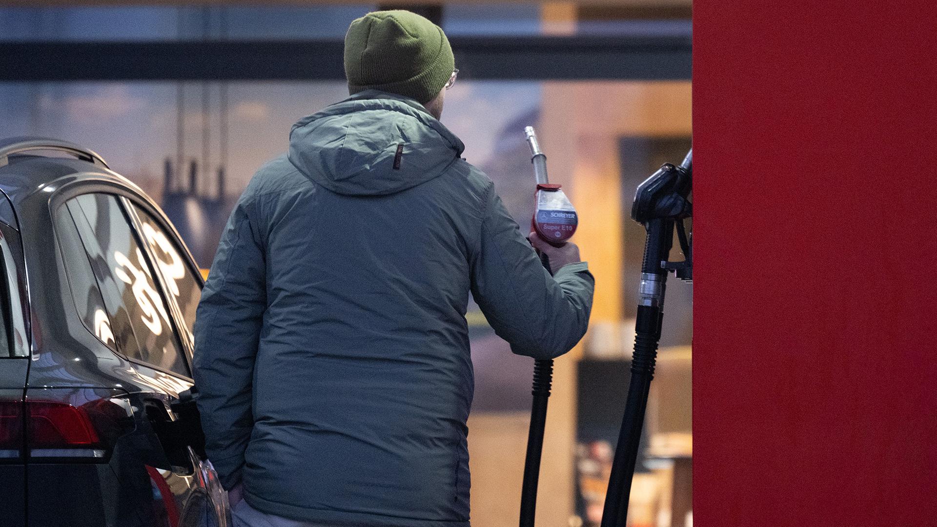 Ein Mann hält an einer Tankstelle eine Zapfpistole. | Sebastian Kahnert/dpa