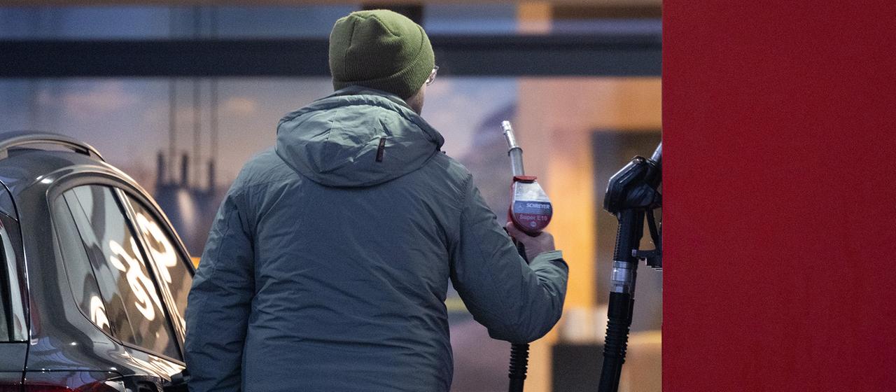 Ein Mann hält an einer Tankstelle eine Zapfpistole.