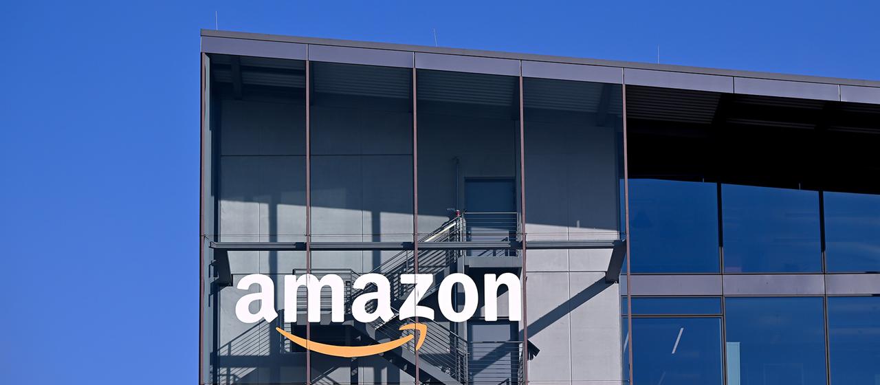 Das Logo und der Schriftzug vom Onlineversandhändler Amazon sind an der Fassade der Zentrale von Amazon Deutschland zu sehen. 