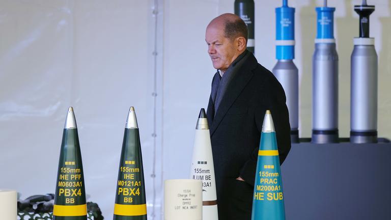 Olaf Scholz geht auf dem Gelände von Rheinmetall an Munition vorbei.