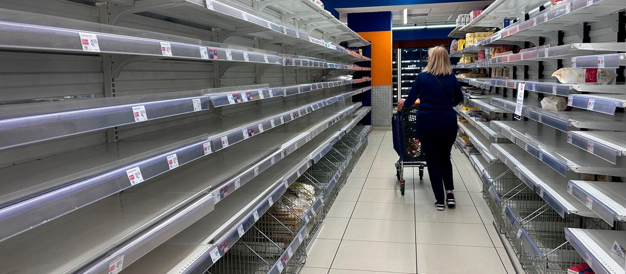Eine Frau geht in einem Supermarkt in Neapel an leeren Regalen vorbei.