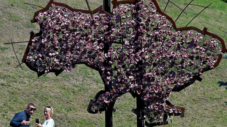 Menschen posieren vor dem aus Blumen gestalteten Umriss der Ukraine 