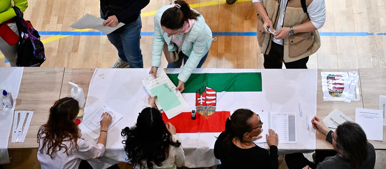 Eine Frau nimmt in einem Wahllokal ihre Unterlagen entgegen.