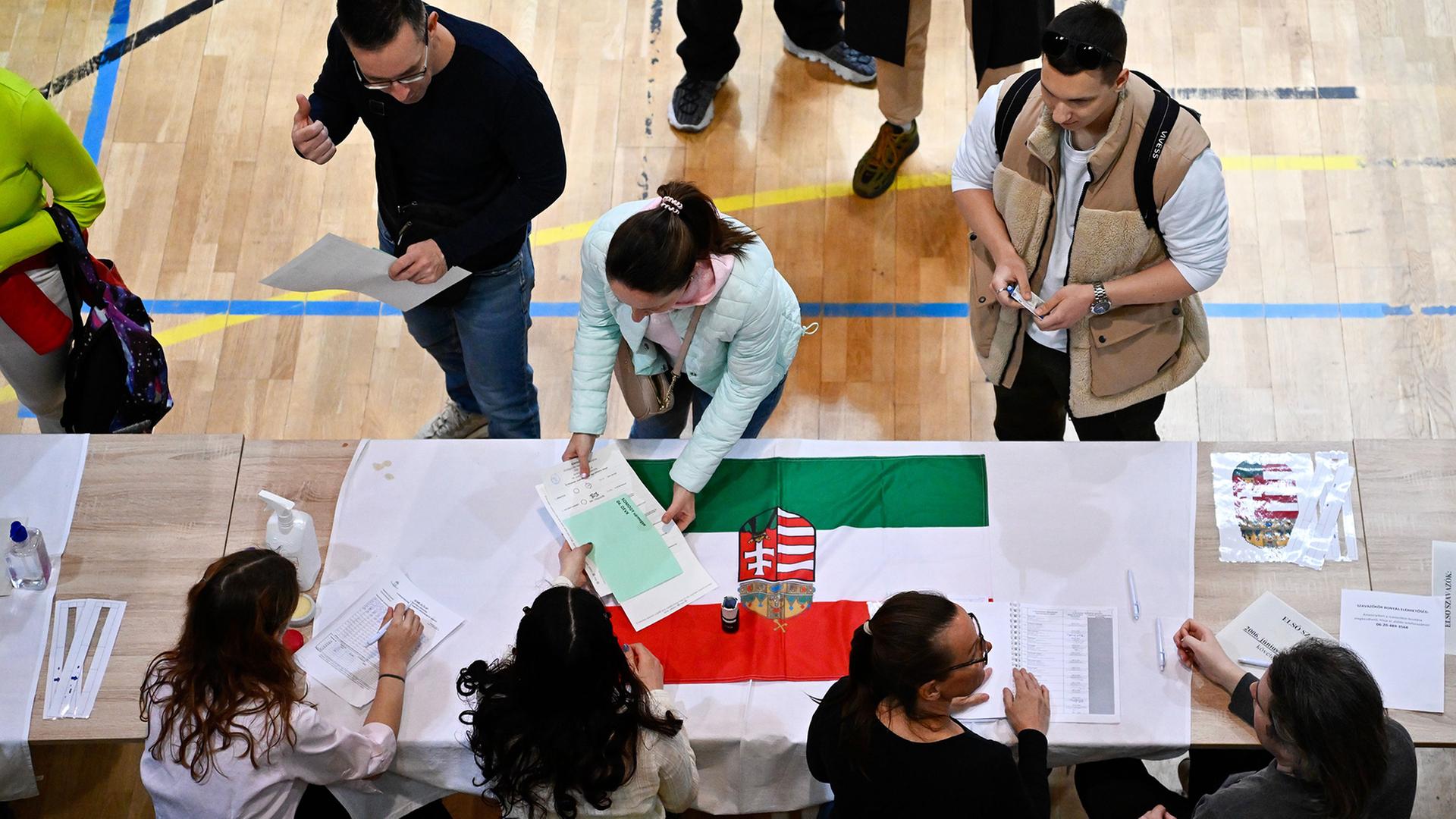 Eine Frau nimmt in einem Wahllokal ihre Unterlagen entgegen. | AP