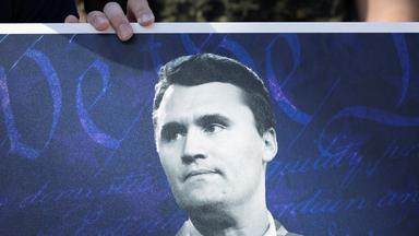 Eine Person hält ein Bild von Charlie Kirk.