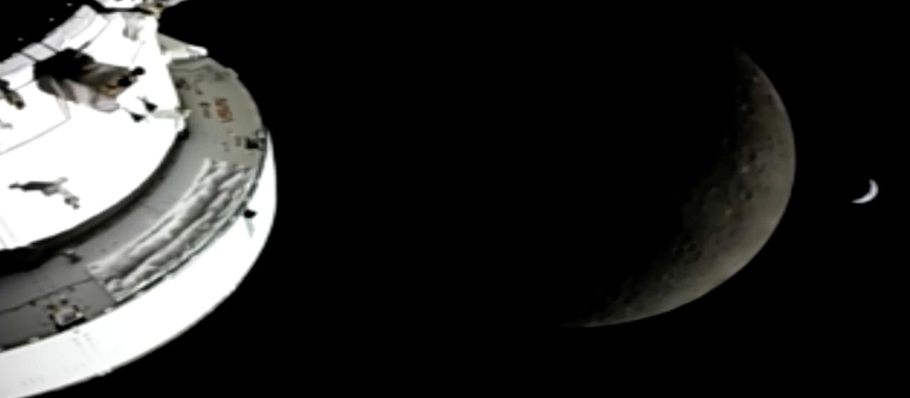 In diesem Bild aus einem von der NASA zur Verfügung gestellten Video sind die "Orion"-Raumkapsel, der Mond und die Erde (r) von einer Kamera aus zu sehen, während die "Artemis 2"-Besatzung und das Raumschiff weiter in den Weltraum vordringen. 