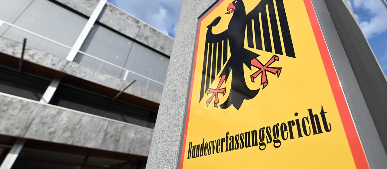 Ein Schild mit der Aufschrift "Bundesverfassungsgericht" mit dem Gebäude im Hintergrund