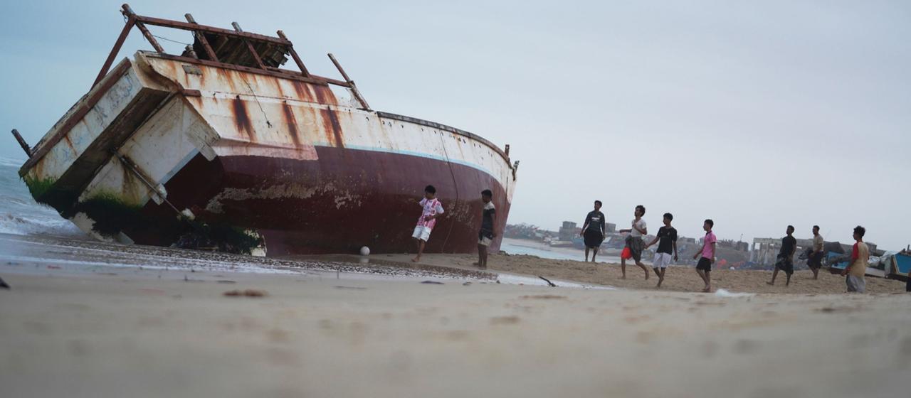Kinder spielen an einem auf dem trockenen liegenden Fischerboot in Mukalla
