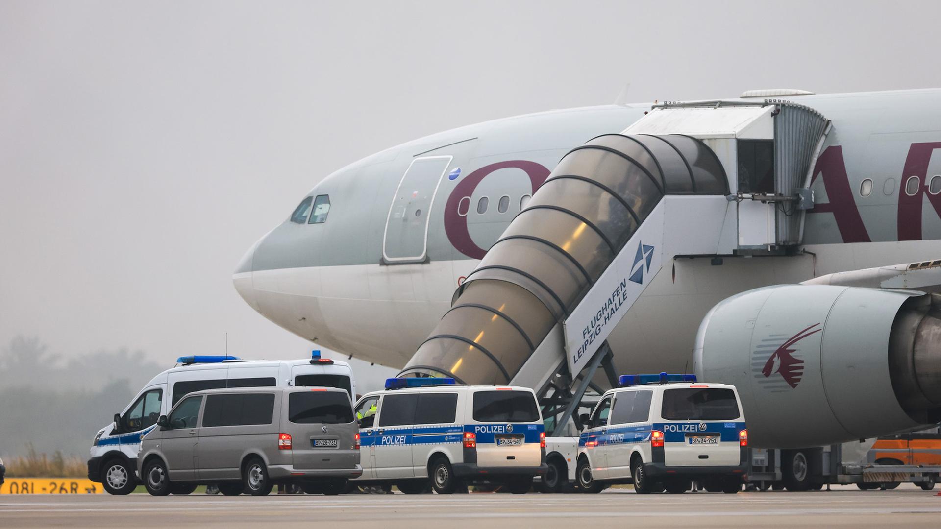 Ein Qatar Airways Flugzeug am Flughafen Leipzig/Halle und Polizeifahrzeuge. | dpa