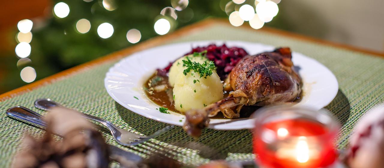 Eine Portion Gänsekeule mit Rotkraut und Klößen steht auf einem Tisch