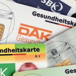 Gesundheitskarten verschiedener Krankenkassen liegen auf einem Tisch.