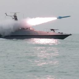 Ein Schiff feuert auf dem Wasser eine Rakete ab und wird von Rauch eingehüllt.