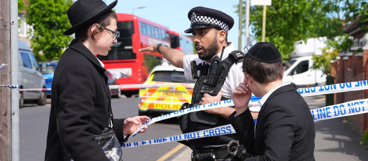 Ein Polizist spricht mit zwei jüdischen Jungen in London