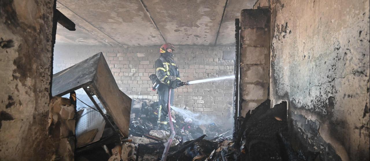 Ein Feuerwehrmann löscht einen Brand in einem Wohngebäude in Charkiw.