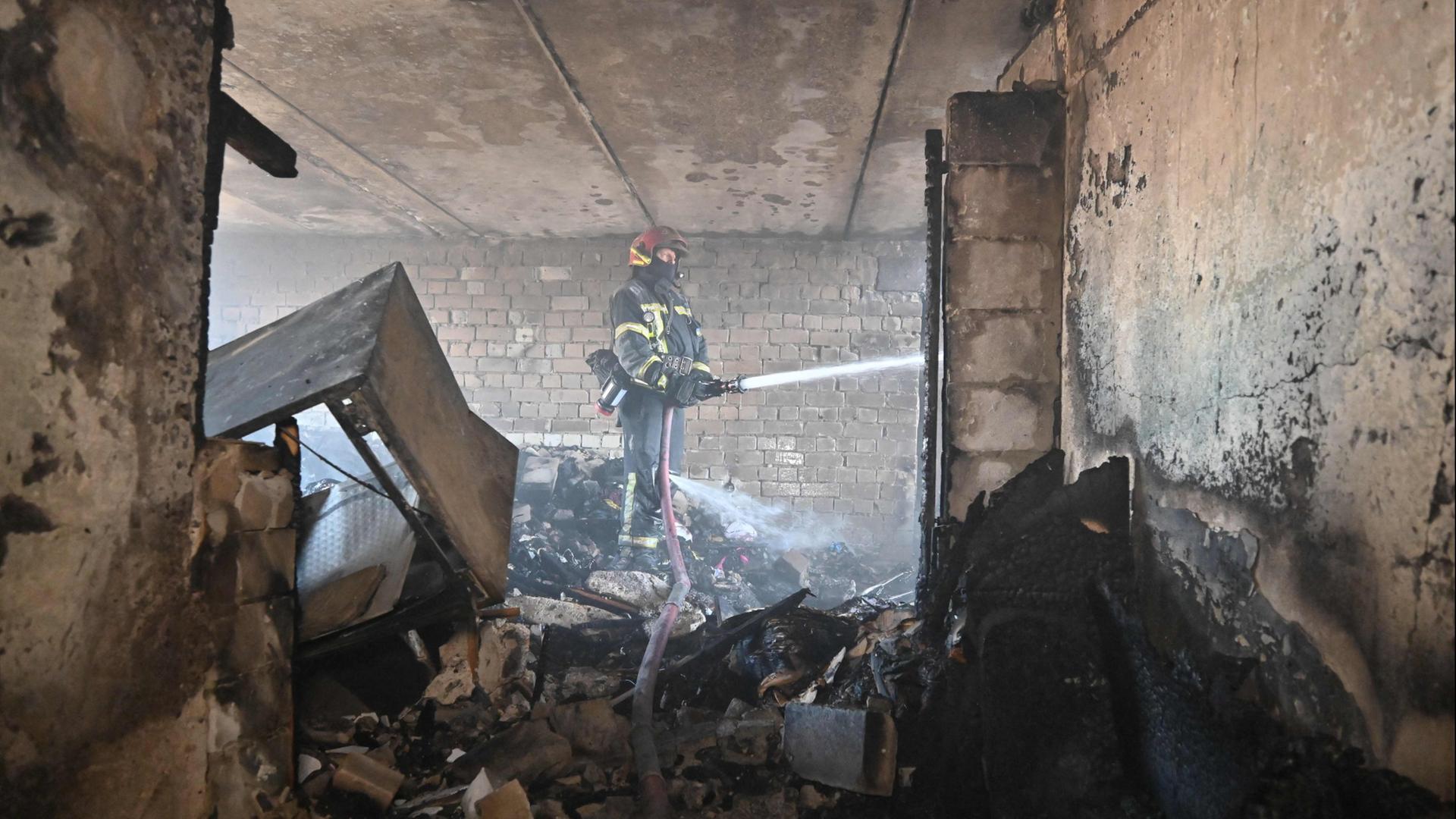 Ein Feuerwehrmann löscht einen Brand in einem Wohngebäude in Charkiw. | AFP