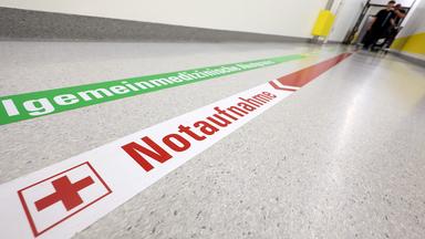 Ein Wegweiser leitet in einem Klinikum zur Notaufnahme.