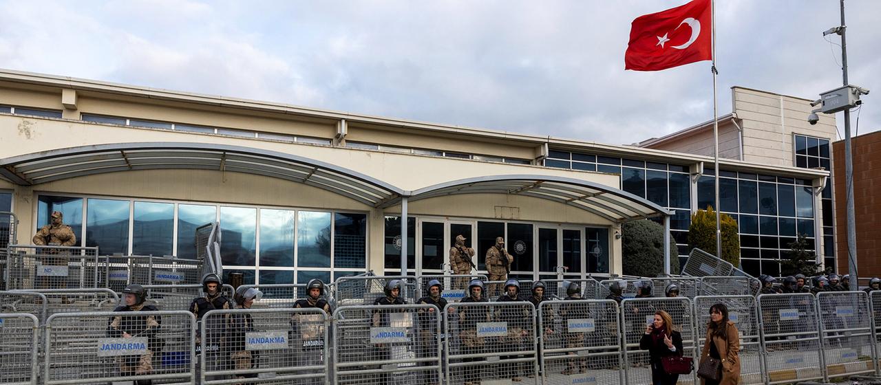Absperrgitter stehen vor einem Gebäude, vor dem die türkische Flagge weht.