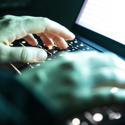 Eine Person tippt mit den Fingern auf einer beleuchteten Laptop-Tastatur.