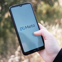 Eine Hand hält eine Smartphone, auf dem das Meta-Logo zu sehen ist.