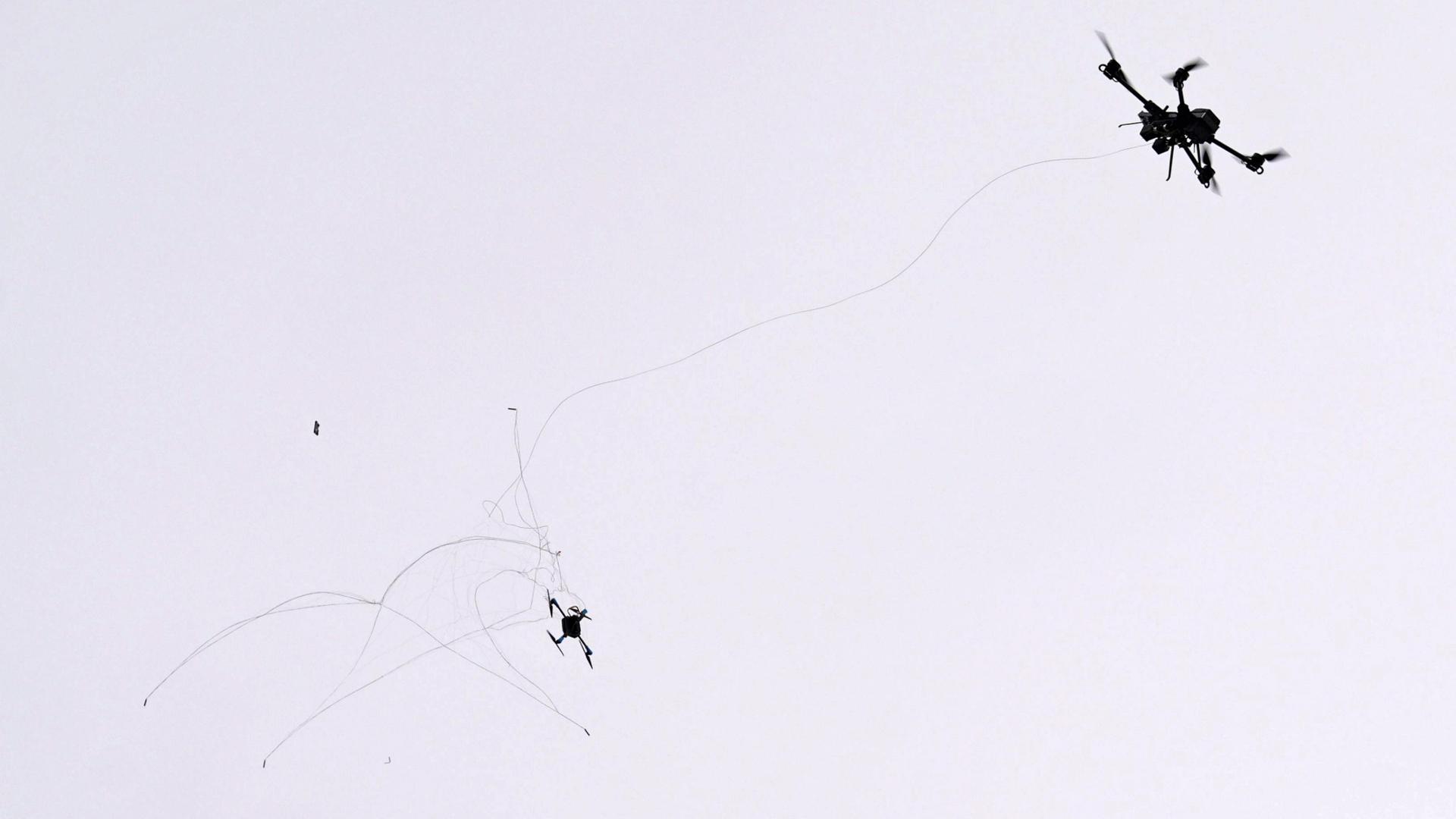 Eine Netzwerferdrohne (r) fängt eine Drohne während einer Übung. | Marcus Brandt/dpa