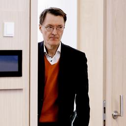 Karl Lauterbach tritt durch eine Tür in einen Konferenzraum 