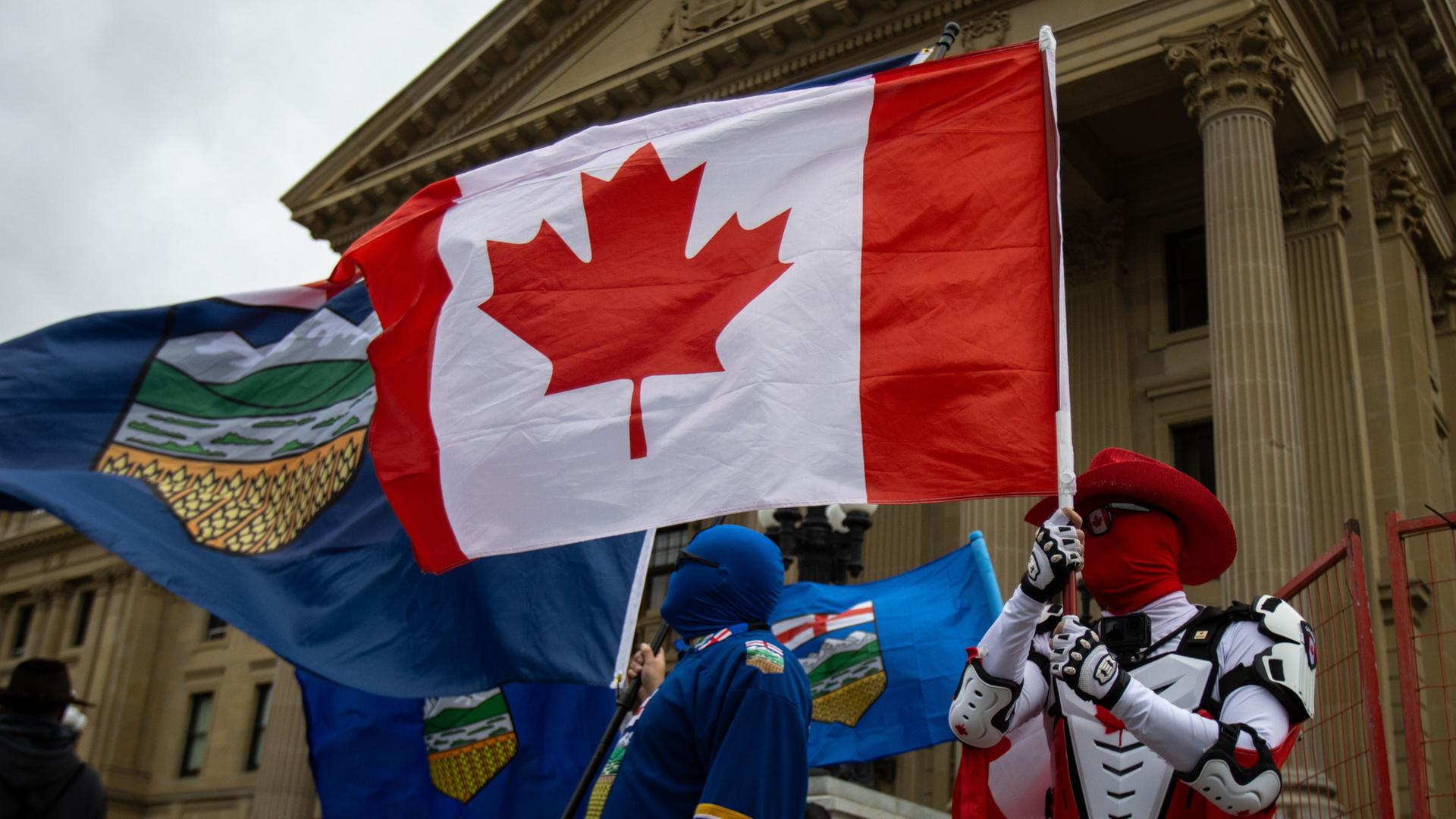 Demonstranten und Gegendemonstranten schwenken die Flaggen von Alberta und Kanada | Amanda May Erickson/The Canadian Press via AP