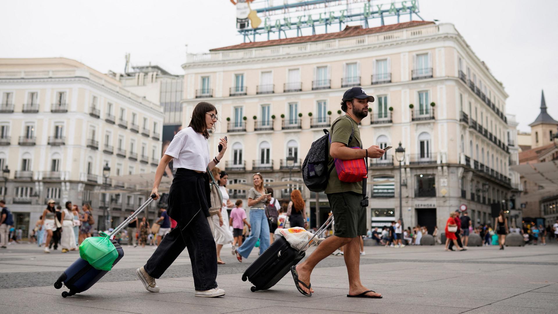 Menschen ziehen ihre Koffer über die Puerta del Sol in Madrid. | REUTERS