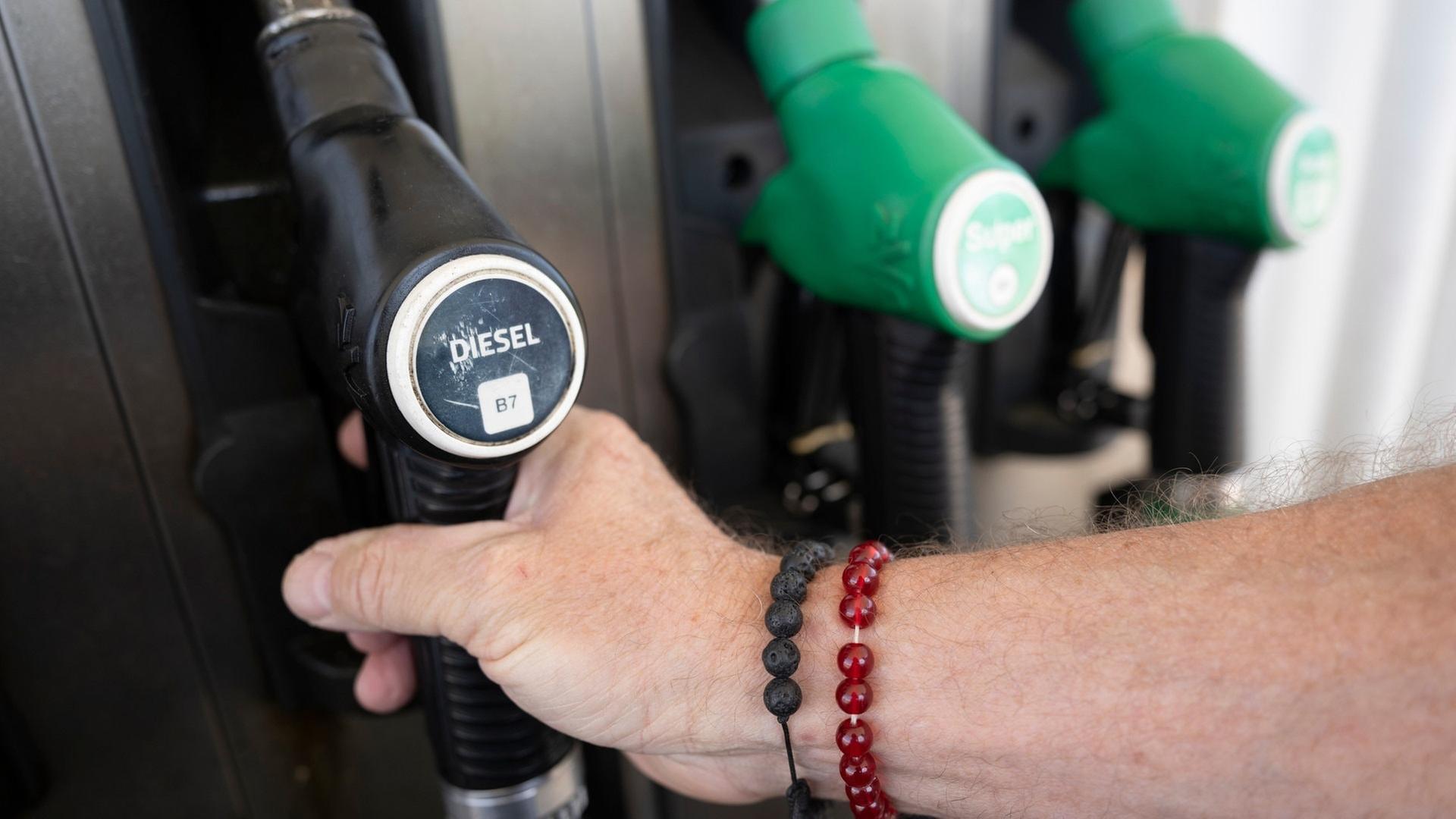 Ein Mann nimmt einen Zapfhahn an einer Tankstelle in die Hand. | dpa Bildfunk, picture alliance/dpa | Marijan Murat