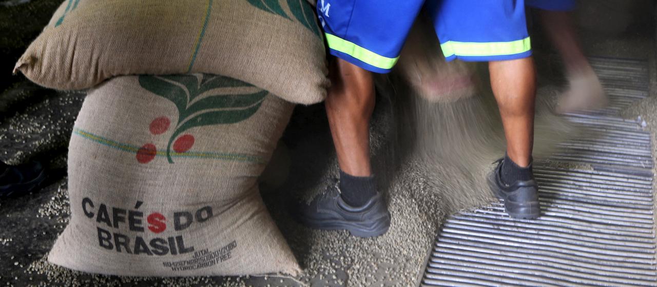 Ein Mann steht neben Säcken mit Kaffeebohnen aus Brasilien