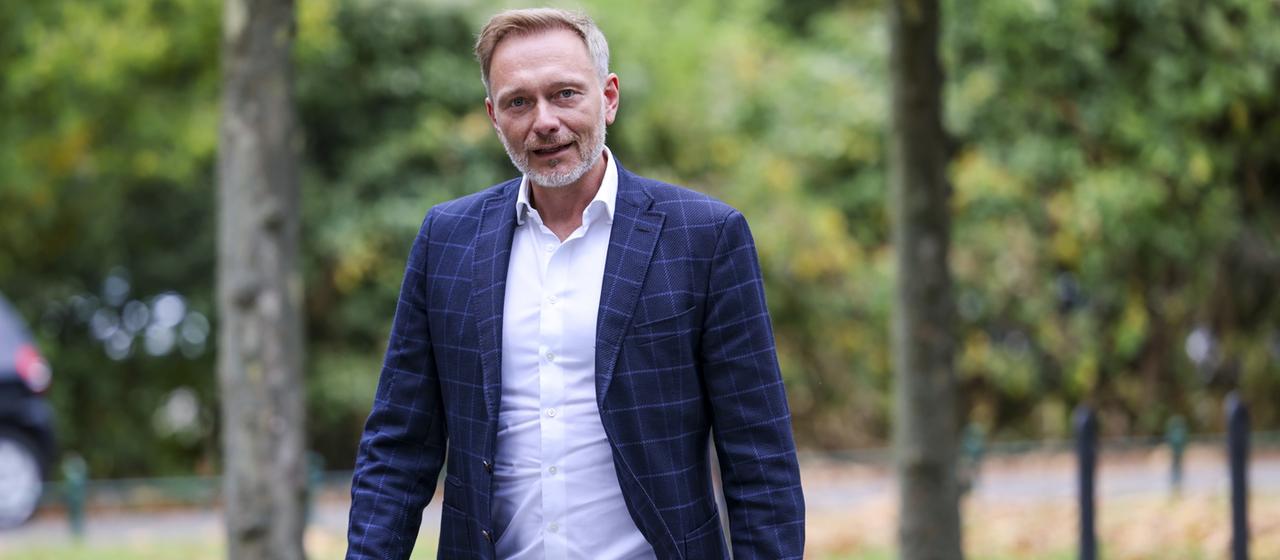 Christian Lindner geht entlang einer Reihe von Bäumen