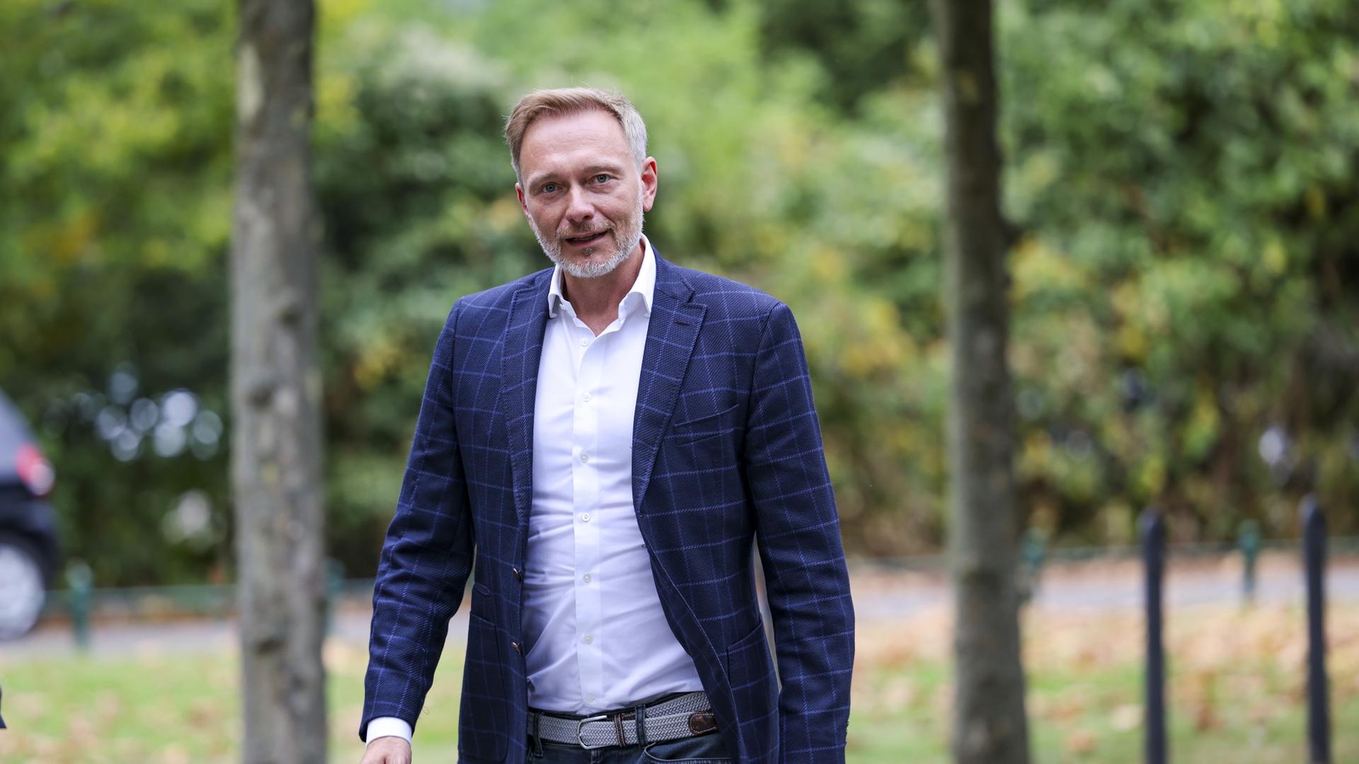 Christian Lindner geht entlang einer Reihe von Bäumen | dpa