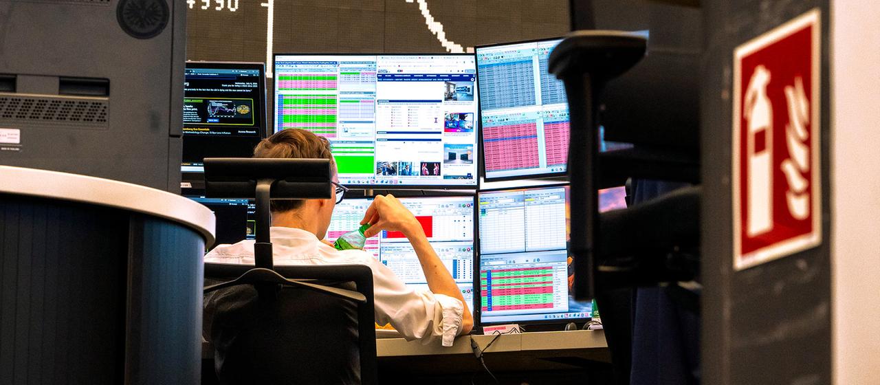Händler an der Frankfurter Börse, fallender Dax-Chart im Hintergrund.