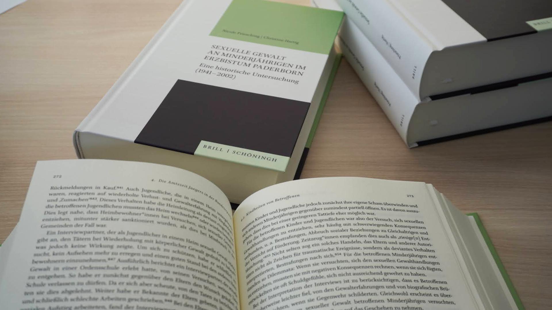 Bücher liegen auf einem Tisch. Das eine Buch hat den Titel 