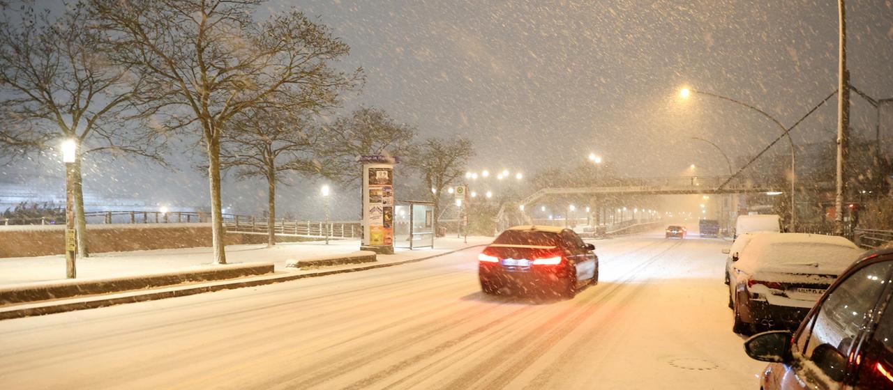 Ein Auto fährt auf einer schneebedeckten Straße in Hamburg. 