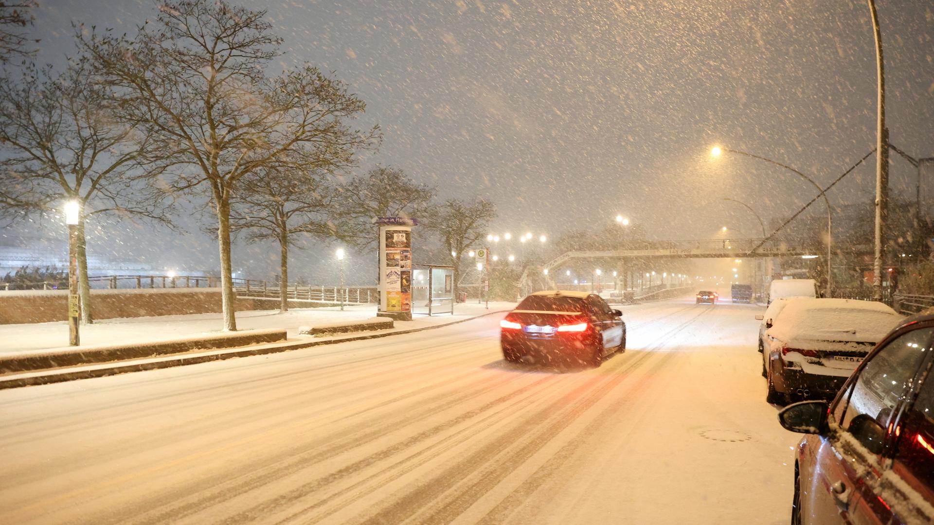 Ein Auto fährt auf einer schneebedeckten Straße in Hamburg.  | dpa