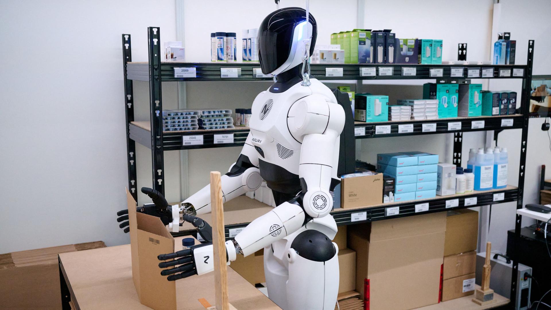 Ein weiß-schwarzer Roboter arbeitet an einem Tisch. | Sven Hoppe/dpa