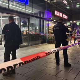 Polizeibeamte stehen vor einem Supermarkt, dessen Eingang nach einem blutigen Streit abgesperrt wurde.