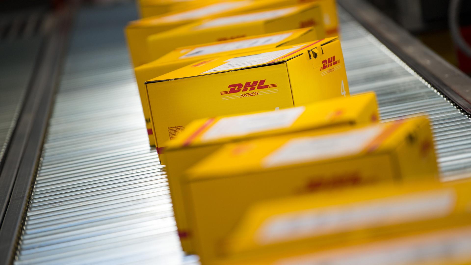 Pakete liegen auf einem Förderband an einem DHL Express-Logistikstandort | dpa