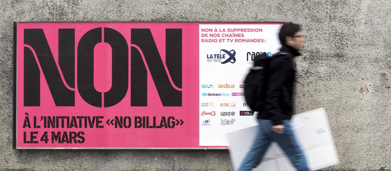 Ein Mann geht an einem Plakat der "No Billag"-Initiative in der Schweiz vorbei.