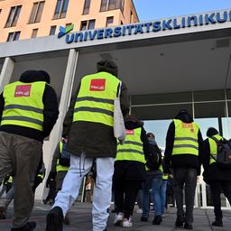 Beschäftigte sind mit Warnwesten vor dem Eingang zum Uniklinikum Jena unterwegs