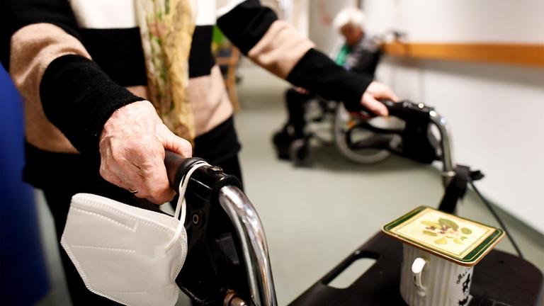 Eine Heimbewohnerin schiebt ihren Rollator durch einen Gang in einem Pflegeheim.